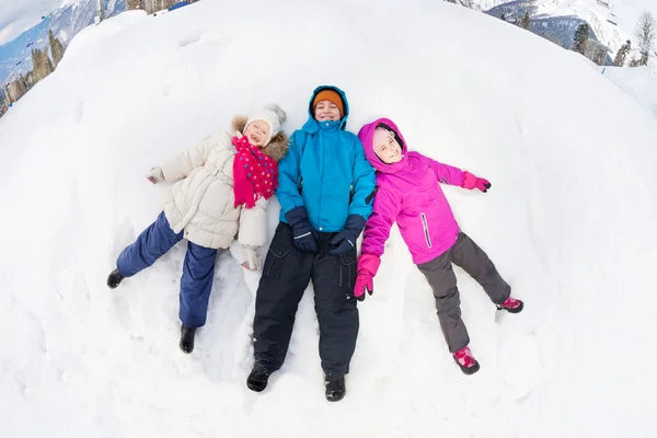 Three kids lay on snow — 图库照片