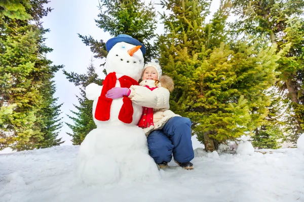 Meisje en sneeuwpop met sjaal samen — Stockfoto