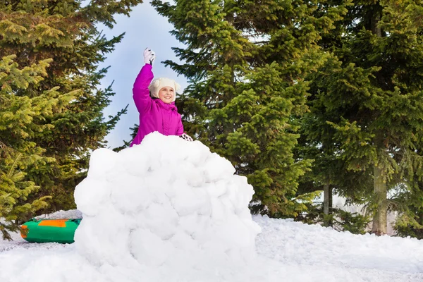 Meisje met sneeuwbal achter sneeuw muur — Stockfoto
