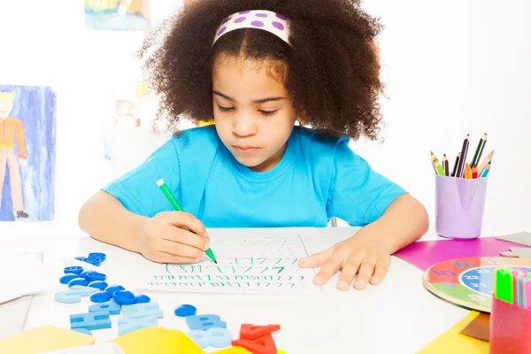 Fille africaine écrivant des lettres avec crayon — Photo