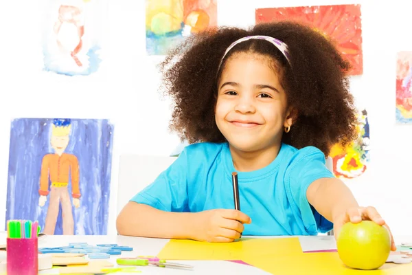 African girl holds pencil and apple — Stockfoto