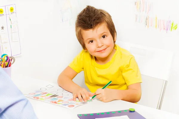 Uśmiechnięty chłopiec kolorując kształty na papierze — Zdjęcie stockowe