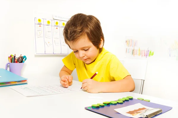 Geconcentreerde kleine jongen met potlood schrijven — Stockfoto