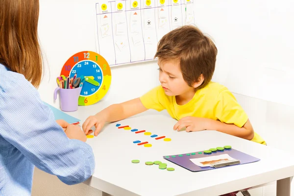 Concentrated boy puts colorful coins — Stockfoto