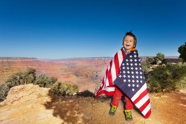 Happy boy bundled up in USA flag — Stock fotografie