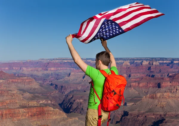 Homem com mochila segurando bandeira americana — Fotografia de Stock