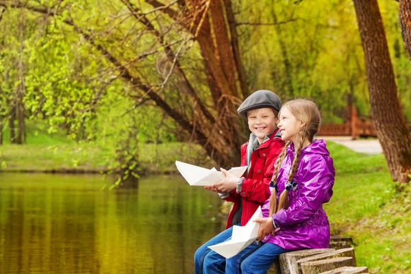 Girl and boy sit near pond — Stock Photo, Image