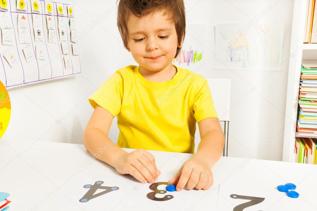 Smiling boy put coins on numbers