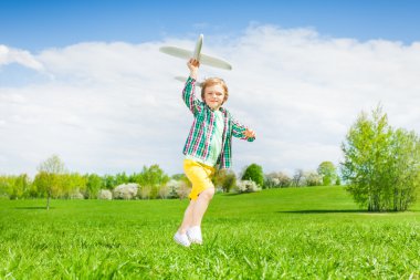 Running small boy holding airplane