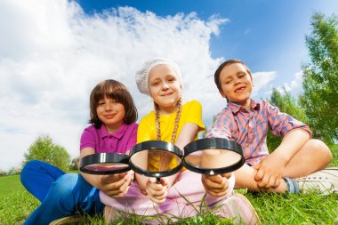 Three kids sitting with magnifiers clipart