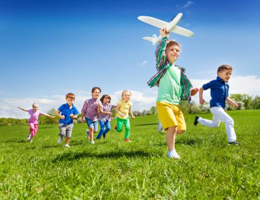 running kids with boy holding airplane