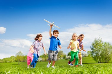 boy with airplane toy and friends running