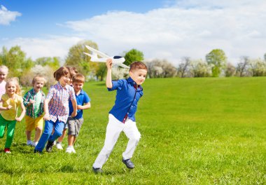 Boy with kids runs with airplane toy