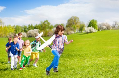 Boy with kids runs with airplane toy