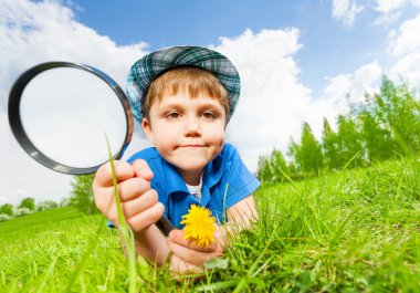 Small boy with hat holds magnifier