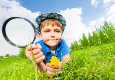 Small boy with hat holds magnifier clipart