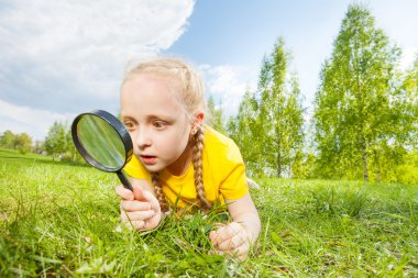 Small girl with magnifier looking