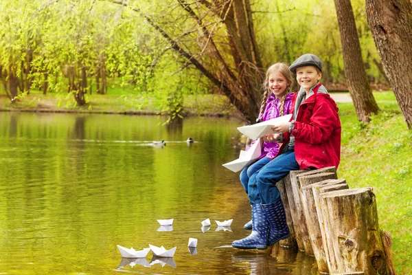 Sitting kids play with paper boats — Stock Photo, Image