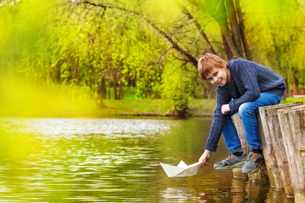 Smiling boy plays with paper boat — Stock Photo, Image