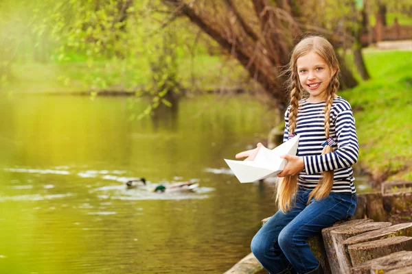 Girl near pond holding paper boat — Stock Photo, Image