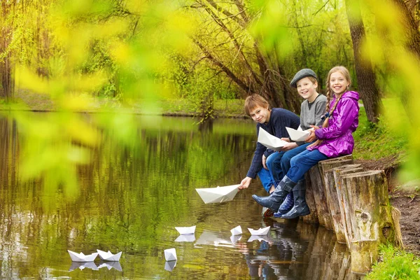 Friends putting paper boats on pond — Stock Photo, Image