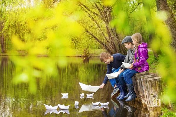 Drei Kinder setzen Papierboote — Stockfoto