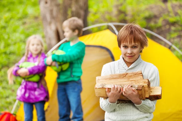 Pojken håller trä för camping brasa — Stockfoto