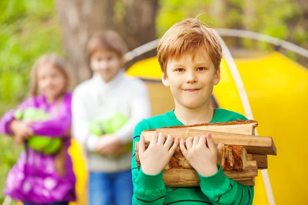 Chlapec hospodářství dřevo na táborák — Stock fotografie