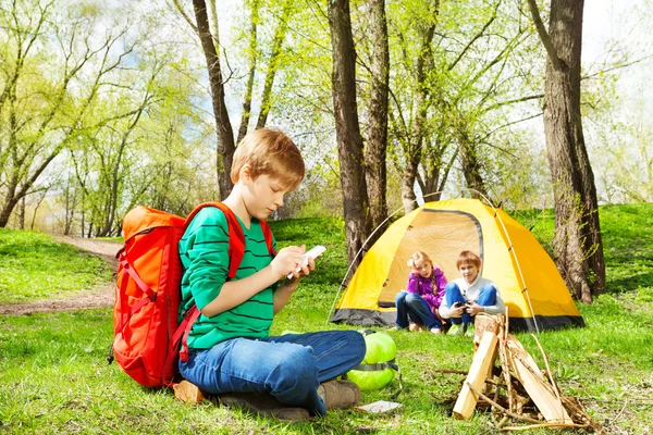 Jongen met rugzak schrijft notebook op camping — Stockfoto