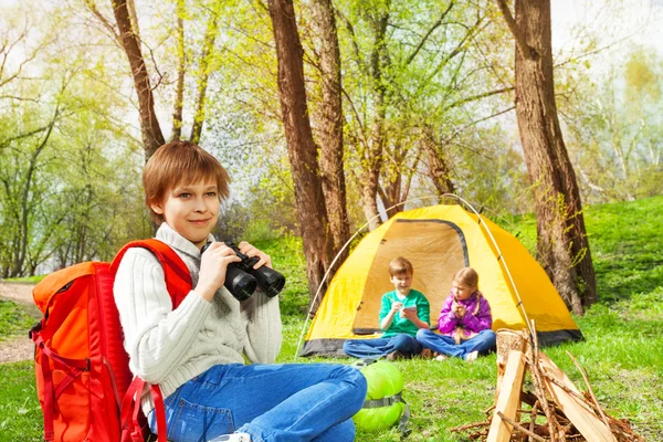 Chlapec s červeným batoh drží binokulární — Stock fotografie