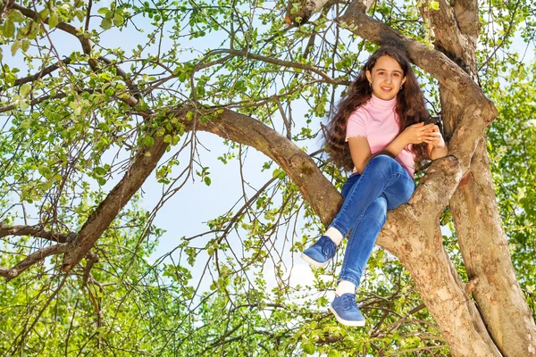 Girl sitting on branch of tree — Stock Photo, Image