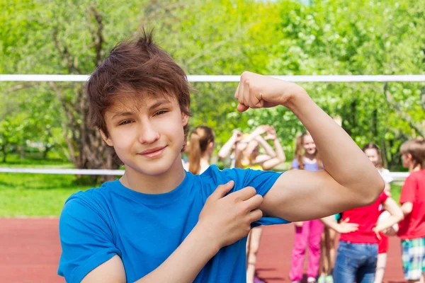 Teenager boy shows bicep muscles — Stock Photo, Image