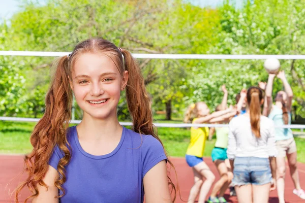 Lächelndes Mädchen mit Mitschülern beim Volleyball — Stockfoto