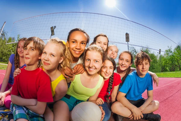 Amigos se sientan en la cancha de voleibol juego — Foto de Stock