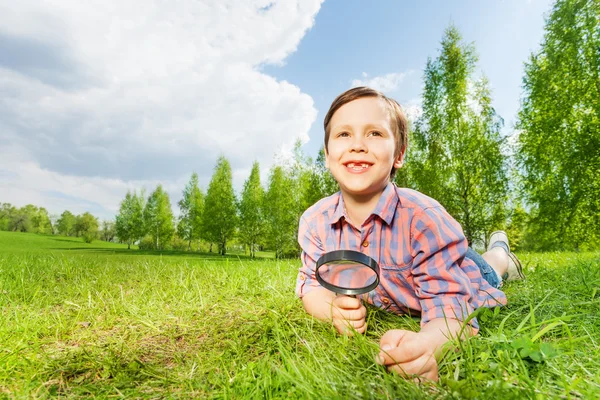 Felice piccolo ragazzo cerca con lente di ingrandimento — Foto Stock