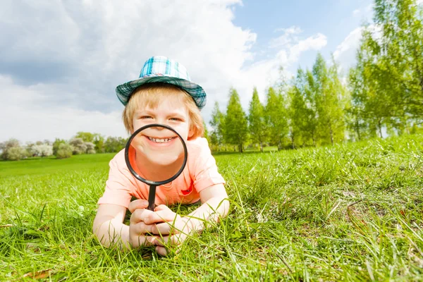 Happy smiling boy lays on grass — ストック写真