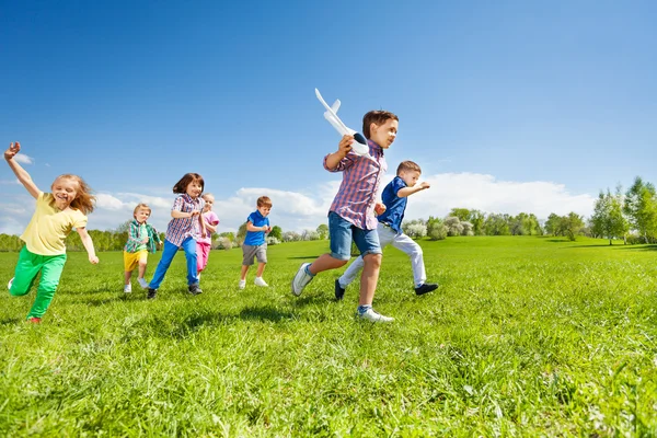 Kids running and boy holding airplane — 스톡 사진