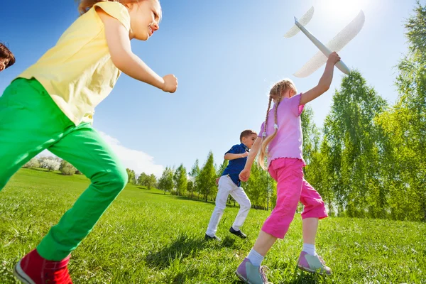 Счастливые бегущие дети с самолетной игрушкой — стоковое фото