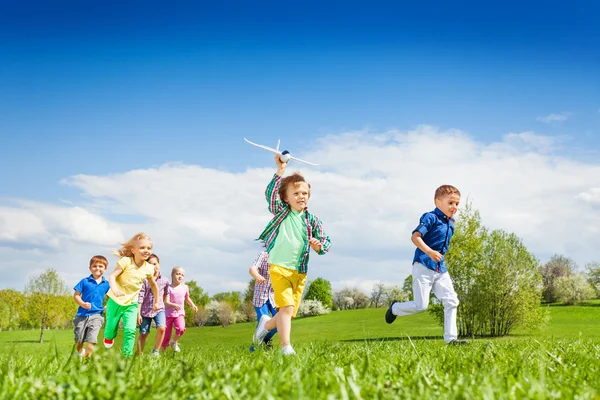 Running boy with airplane toy and children — Stockfoto