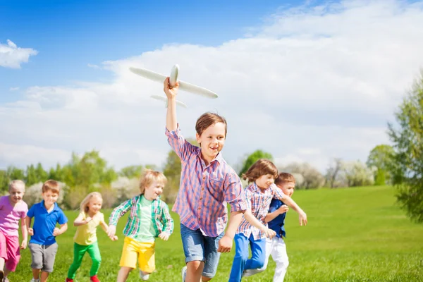 Boy with kids runs with airplane toy — ストック写真