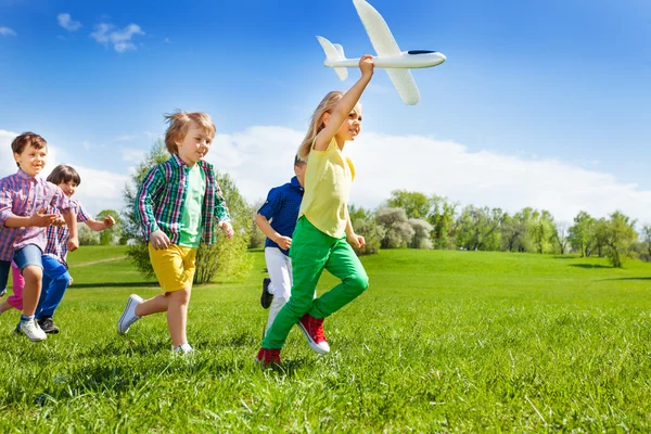 Running kids and girl holding airplane — Stock Fotó