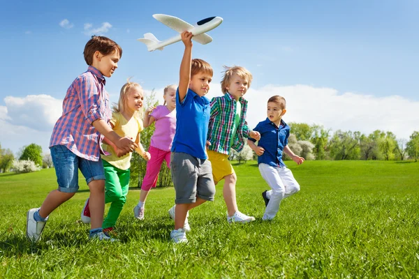 Boy with kids runs with airplane toy — Stockfoto