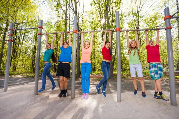 Happy teens chinning up on playground — Stock Image Happy teens chinning up on playground Stock Image