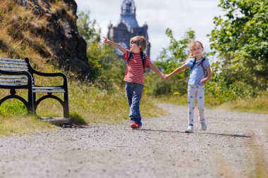 Canton Hill 'de parlak bir yolda yürüyen iki çocuk yaz gezisinde el ele tutuşurken, bir tanesi hevesle el ele tutuşuyor, Edinburg, İskoçya