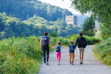Çocuklu anne, yazın İngiltere 'de, gelişen eğrelti otları ve ağaçlarla çevrili Howden Reservoir boyunca doğa yolunda yürürken el ele tutuşur.