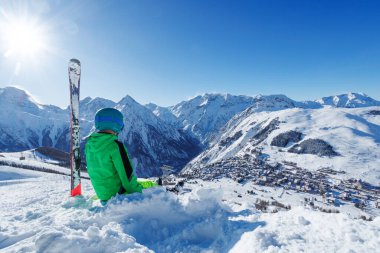 Genç bir genç neon-yeşil dişli tepe kenarında durur, karın üzerinde oturur ve ilerideki uçsuz bucaksız alp zirvelerini soğurur.