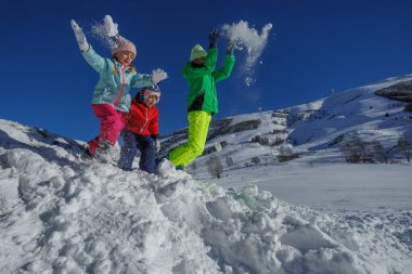 Mutlu kardeşlerim parlak ceketler giyip elleri karla dolu güneşli bir yamaçta kışın gökyüzünün altında gülümsüyorlar.