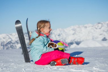 Mavi bir kayak ceketi giyen bir çocuğun yakın portresi, uzaktaki dağlar kameraya doğru dönerken yavaşça bulanıklaştı
