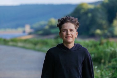 Genç bir gezgin, İngiltere 'nin yeşil çimenleriyle çevrili büyük bir Howden rezervuarı önünde sırıtır.