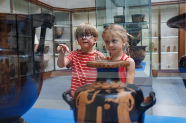 Okul gezisinde bir müze sergisinde objelere dikkatle bakan iki genç.